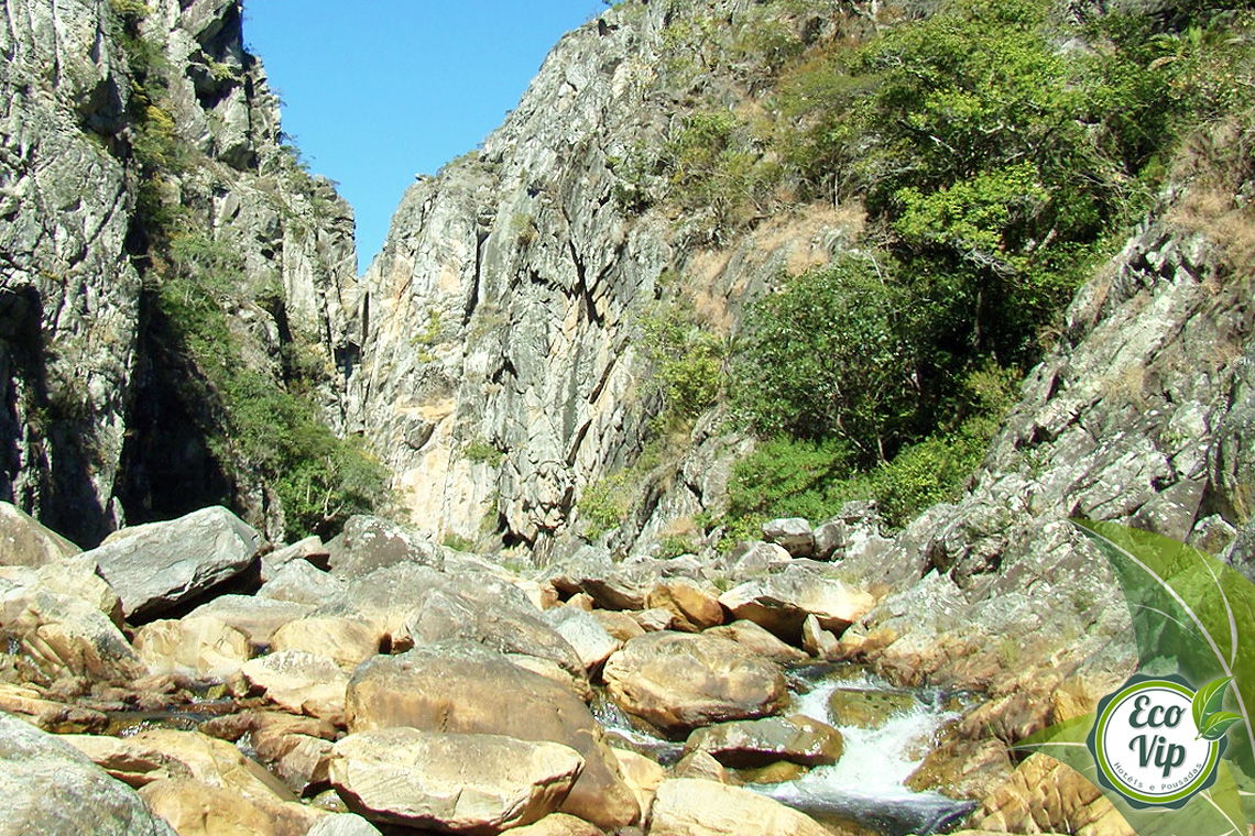 Agua correndo por pedras entre morros na Serra do Cipó